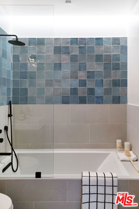 bathroom with tiled shower / bath combo and toilet