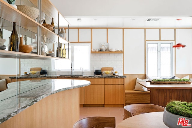 kitchen with sink, light tile patterned flooring, and dark stone counters