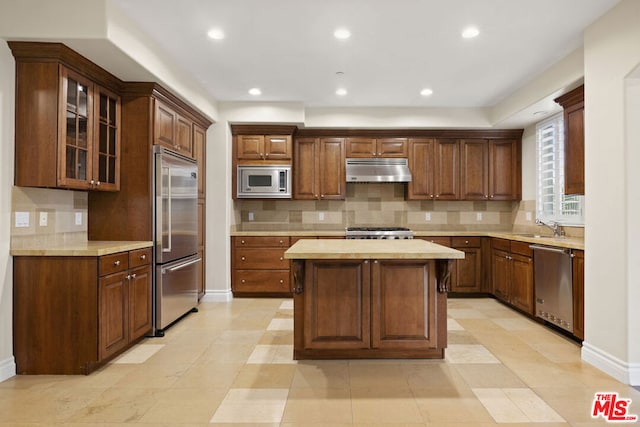 kitchen featuring sink, tasteful backsplash, butcher block countertops, built in appliances, and a kitchen island