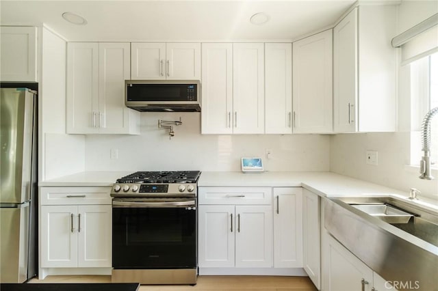 kitchen with plenty of natural light, sink, white cabinetry, and stainless steel appliances