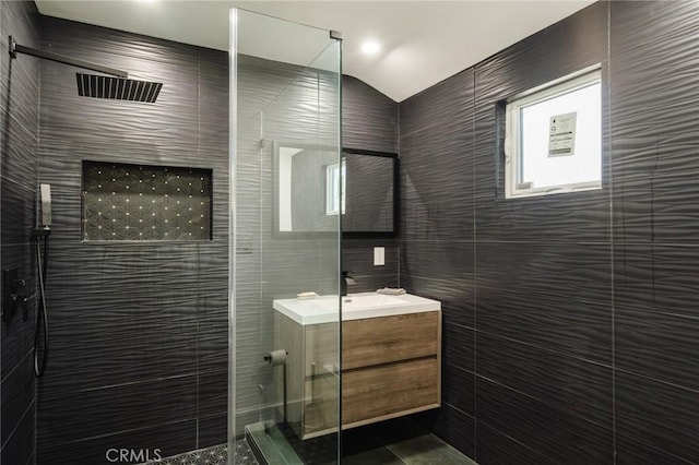 bathroom featuring a tile shower, vanity, and tile walls