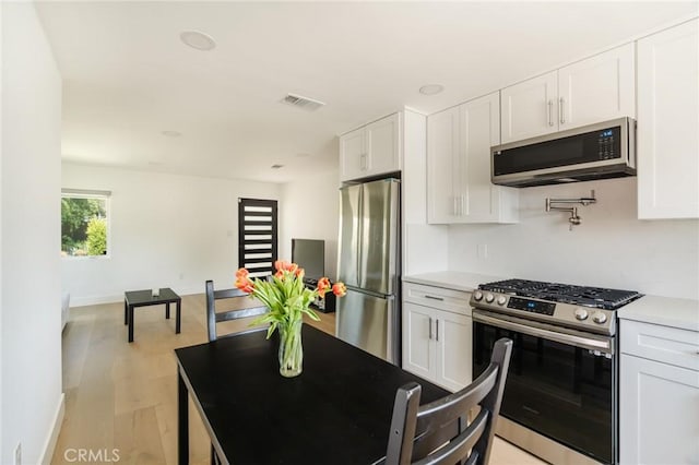 kitchen with white cabinetry, light hardwood / wood-style floors, and appliances with stainless steel finishes