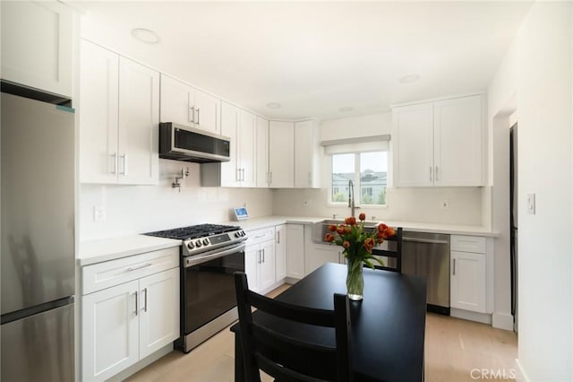 kitchen featuring sink, white cabinets, light hardwood / wood-style flooring, and appliances with stainless steel finishes