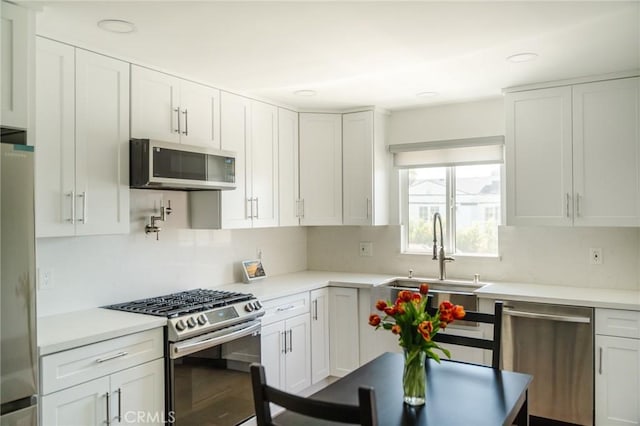 kitchen featuring stainless steel appliances, white cabinetry, tasteful backsplash, and sink