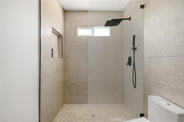 bathroom featuring a tile shower, tile walls, and toilet