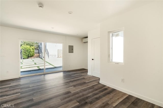 empty room with a wealth of natural light, dark hardwood / wood-style flooring, electric panel, and a wall mounted AC