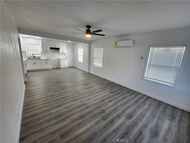 unfurnished living room featuring a wall mounted AC, ceiling fan, sink, and a wealth of natural light