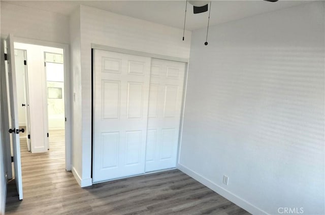 unfurnished bedroom featuring ceiling fan, a closet, and hardwood / wood-style floors