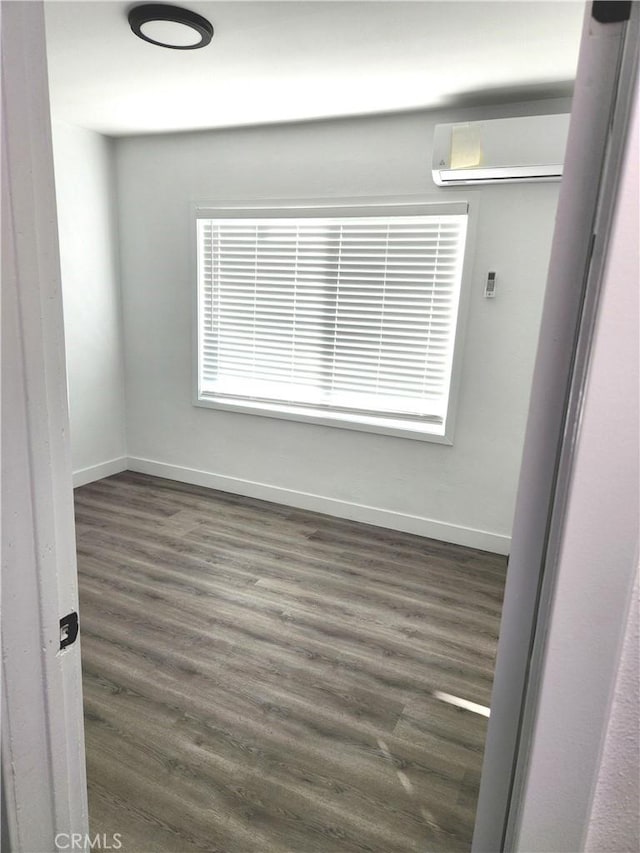 spare room featuring dark hardwood / wood-style flooring and a wall unit AC