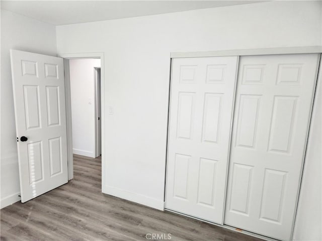 unfurnished bedroom with a closet and light wood-type flooring