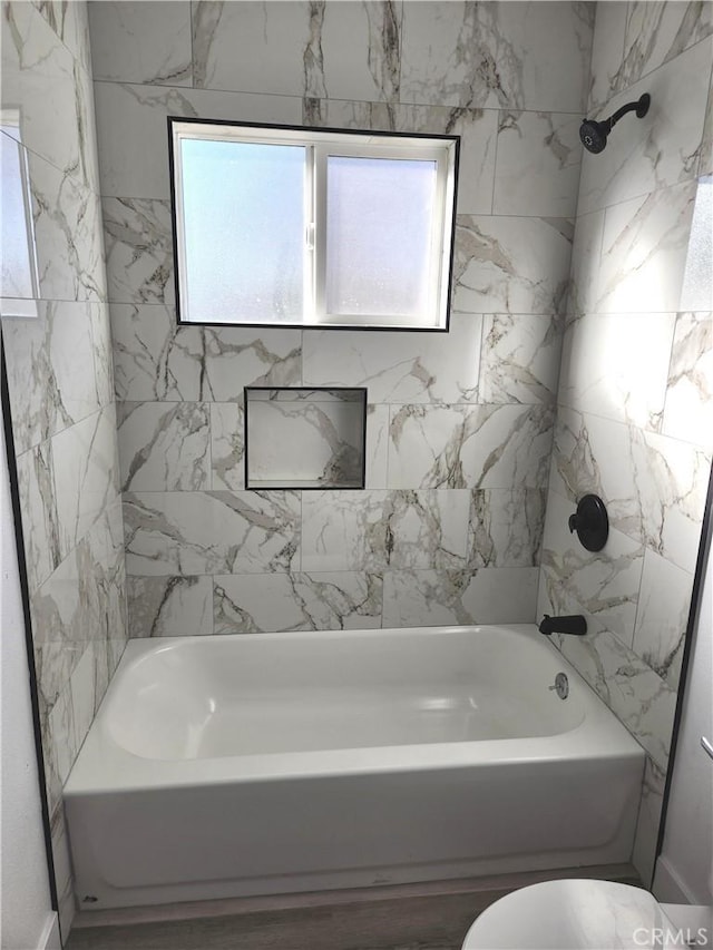 bathroom with toilet and tiled shower / bath