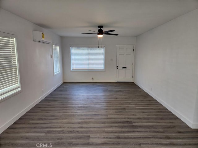 empty room featuring a wall unit AC, ceiling fan, and dark wood-type flooring