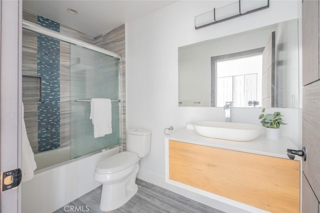 full bathroom featuring wood-type flooring, vanity, enclosed tub / shower combo, and toilet