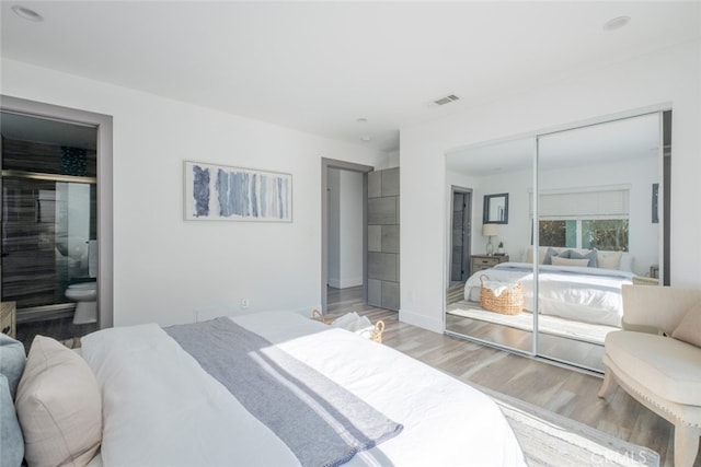 bedroom featuring hardwood / wood-style floors, ensuite bath, and a closet