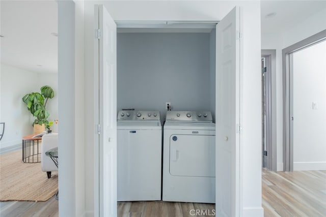 clothes washing area with light hardwood / wood-style flooring and independent washer and dryer