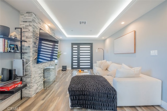 living room featuring a tray ceiling and light hardwood / wood-style floors