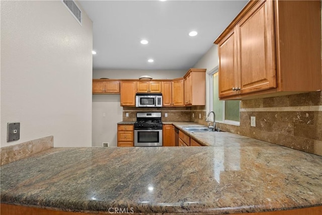 kitchen featuring tasteful backsplash, kitchen peninsula, sink, and appliances with stainless steel finishes