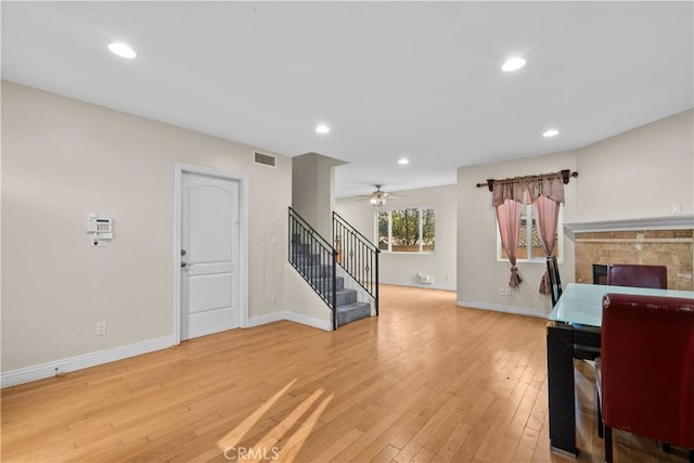 interior space featuring light hardwood / wood-style floors, ceiling fan, and a tiled fireplace