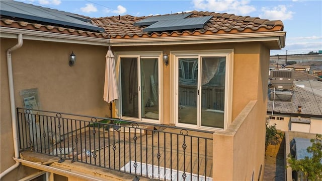 view of property exterior featuring solar panels and a balcony