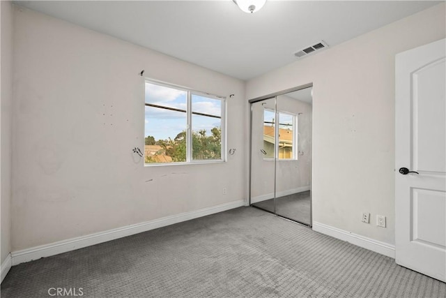 unfurnished bedroom featuring light carpet and a closet