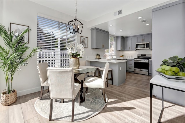 dining space featuring sink, a notable chandelier, and light wood-type flooring