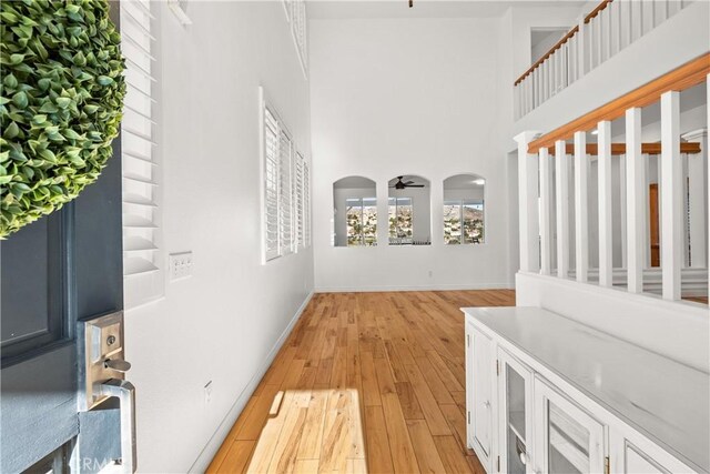 corridor with a towering ceiling and light hardwood / wood-style flooring