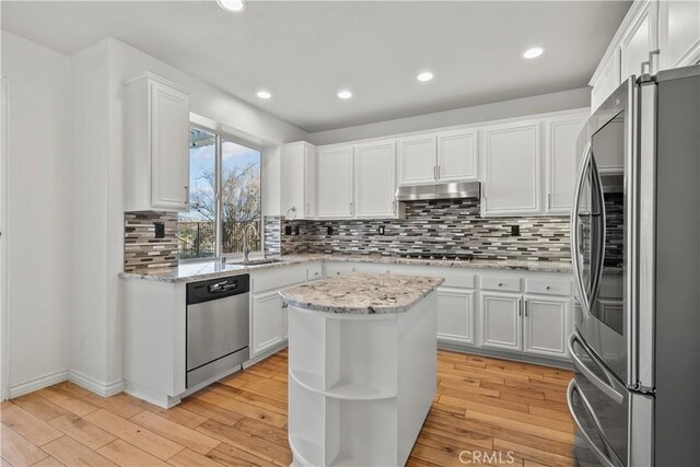 kitchen with white cabinets, a center island, light stone countertops, and appliances with stainless steel finishes