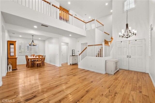 foyer featuring light wood-type flooring and a towering ceiling