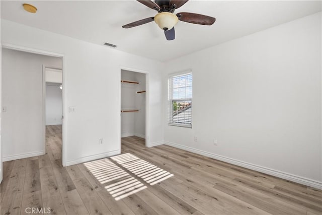 unfurnished bedroom with ceiling fan, a walk in closet, and a closet