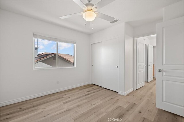 unfurnished bedroom with light wood-type flooring, a closet, and ceiling fan