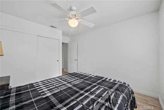 unfurnished bedroom with wood-type flooring, a closet, and ceiling fan