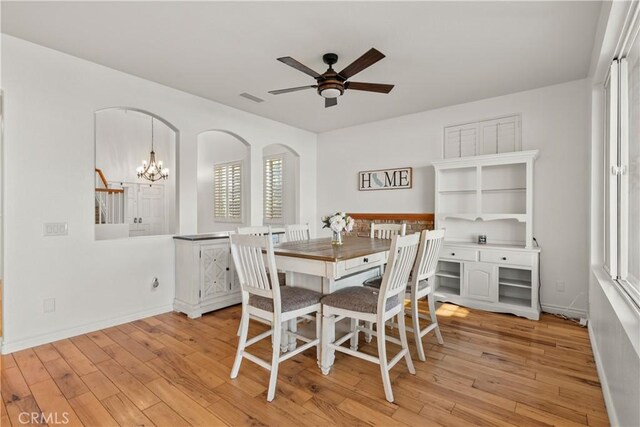 dining space featuring ceiling fan with notable chandelier and light wood-type flooring