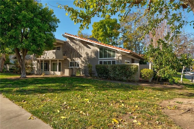 view of front of property with a balcony and a front lawn