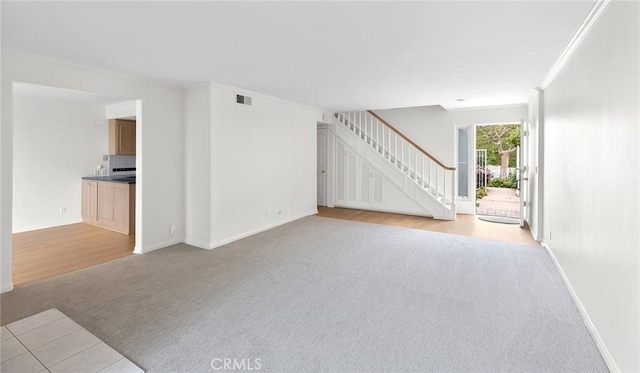 unfurnished living room with crown molding and light colored carpet