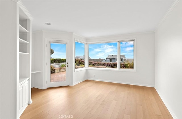 spare room with light wood-type flooring and crown molding