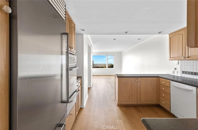 kitchen featuring light brown cabinets, backsplash, light hardwood / wood-style flooring, kitchen peninsula, and stainless steel appliances