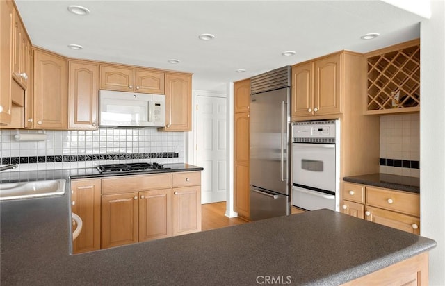 kitchen featuring backsplash, sink, light wood-type flooring, and appliances with stainless steel finishes