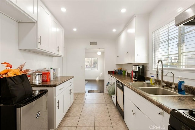 kitchen featuring sink, light tile patterned floors, dishwasher, range, and white cabinetry