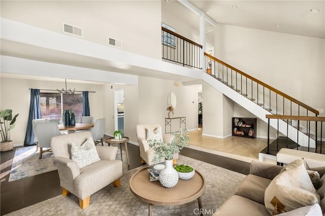 living area with a chandelier, a high ceiling, stairway, and visible vents