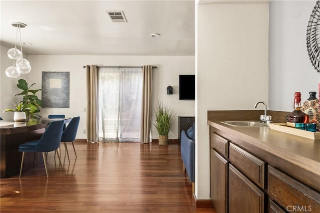 interior space featuring dark wood-style floors, a sink, visible vents, recessed lighting, and pendant lighting