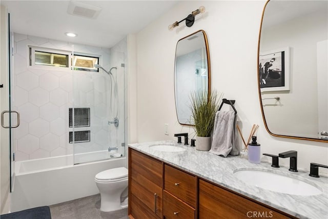 full bath featuring a sink, enclosed tub / shower combo, toilet, and double vanity