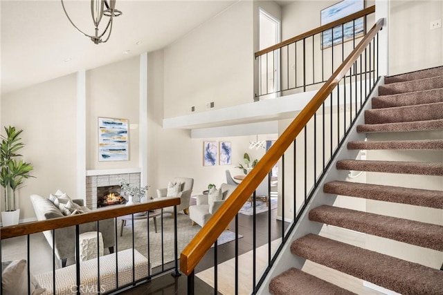 staircase with high vaulted ceiling, visible vents, and a tiled fireplace