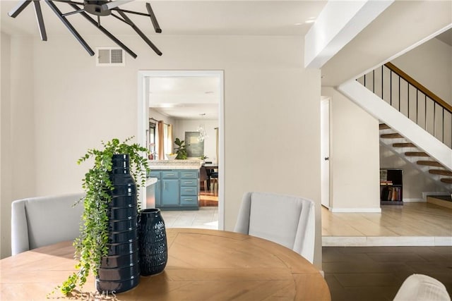 dining space with baseboards, visible vents, a ceiling fan, wood finished floors, and stairs