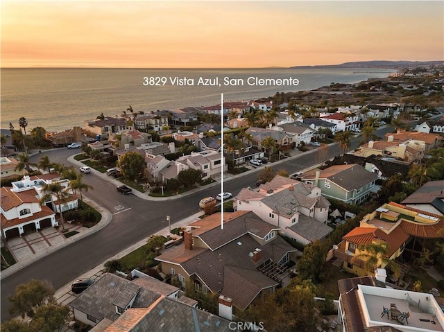 aerial view at dusk featuring a water view