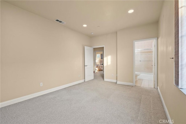 unfurnished bedroom featuring light carpet and connected bathroom