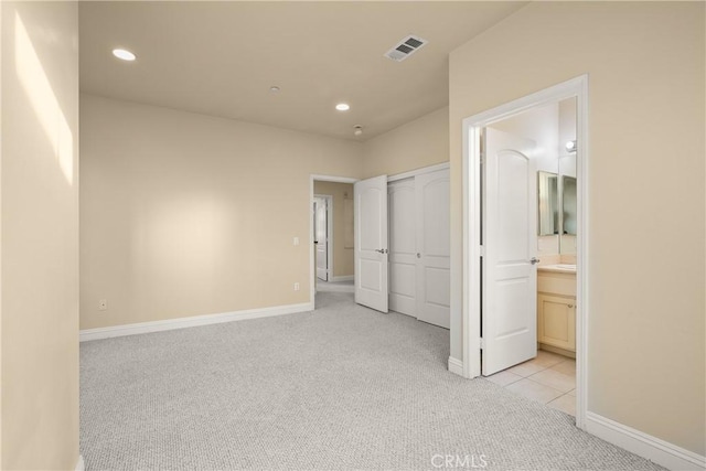 unfurnished bedroom featuring light carpet and connected bathroom