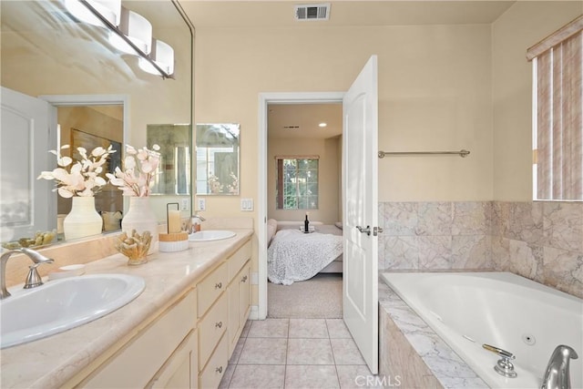 bathroom with tile patterned flooring, vanity, and tiled bath