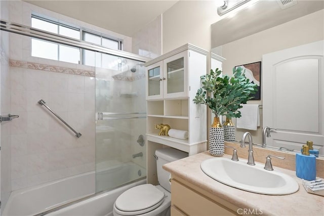 full bathroom with vanity, enclosed tub / shower combo, and toilet