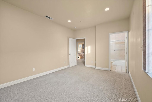 unfurnished bedroom featuring light colored carpet and ensuite bath