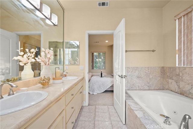 bathroom featuring tile patterned flooring, tiled tub, and vanity